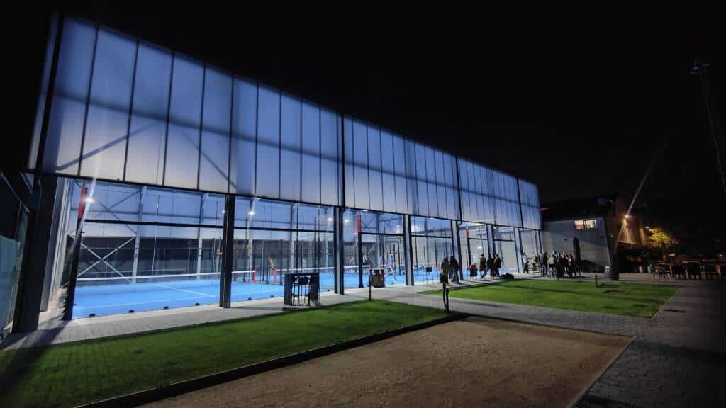 Hall sportif avec façade translucide d’un hall sportif ModuHome éclairé de nuit avec structure acier visible.