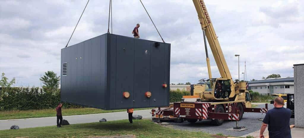 Levage d’un module technique ModuHome gris par grue sur chantier.