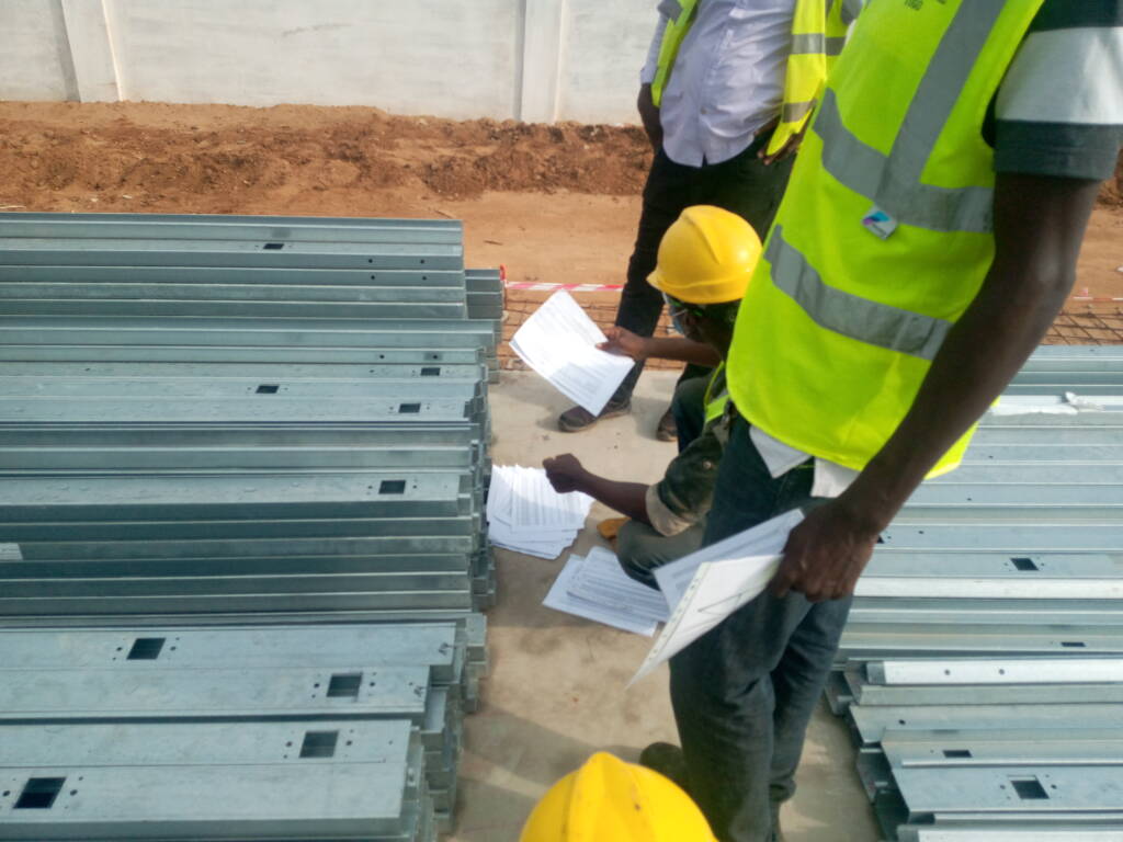 Technicien ModuHome inspectant des profilés acier et des plans sur chantier.