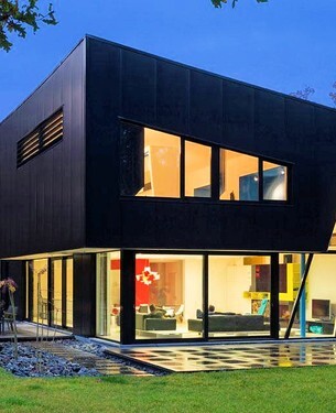 Maison moderne ModuHome en ossature métallique avec façade noire et grandes baies vitrées.
